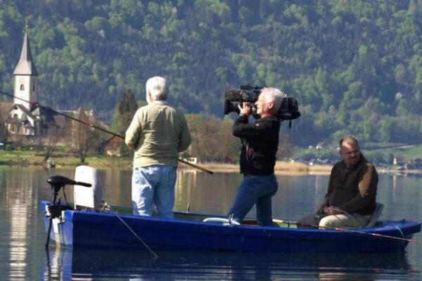 FischZeit in Kärnten Drei Personen im Boot beim Angeln auf dem Ossiacher See, mit einem Kameramann, der das Angeln dokumentiert.