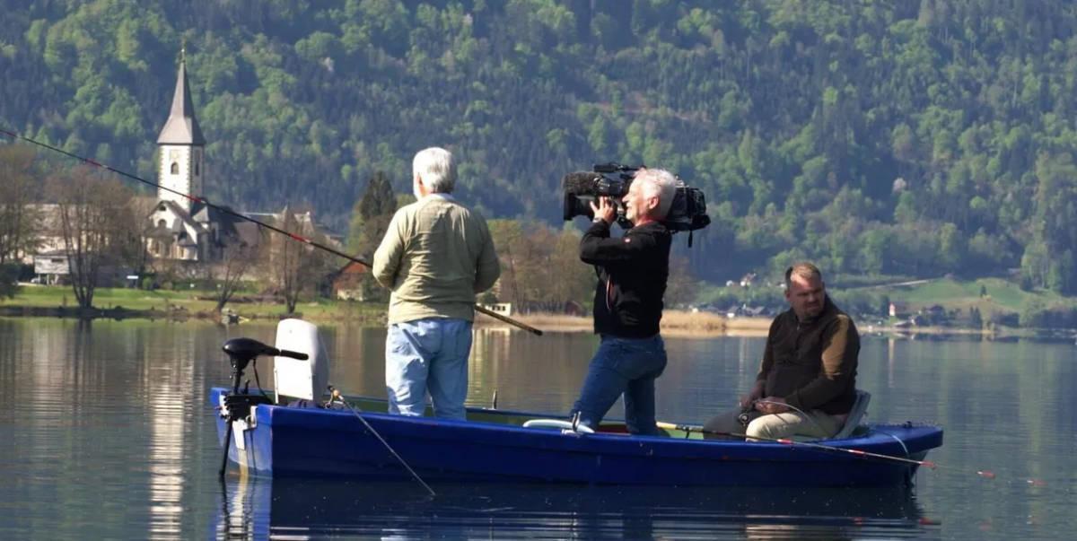 Drei Personen im Boot beim Angeln auf dem Ossiacher See, mit einem Kameramann, der das Angeln dokumentiert.